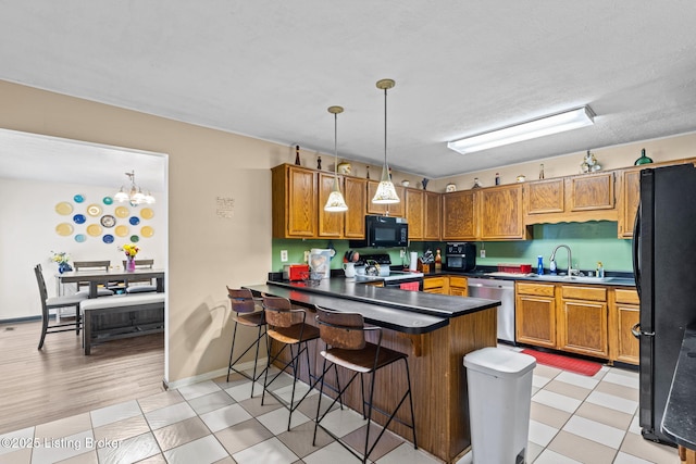 4308 Fence Pl, Louisville, KY 40241 - kitchen with black appliances, a sink, a peninsula, brown cabinetry, and hanging light fixtures