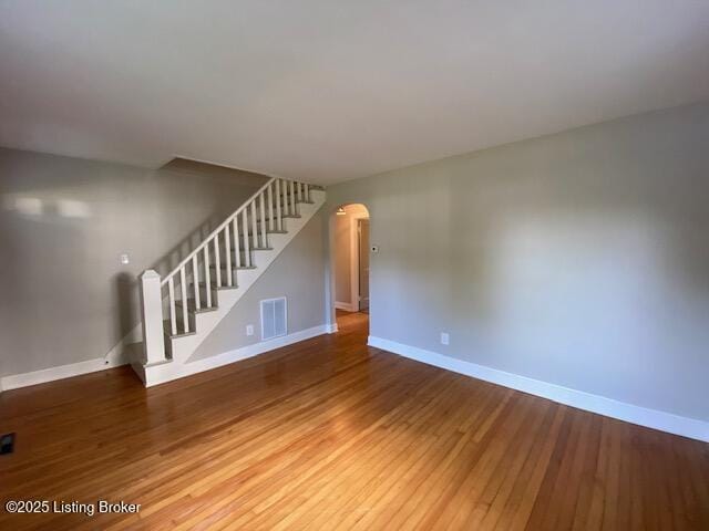 820 Johnson St, Bardstown, KY 40004 - unfurnished living room with arched walkways, baseboards, wood finished floors, and stairway