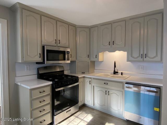 820 Johnson St, Bardstown, KY 40004 - kitchen with appliances with stainless steel finishes, a sink, light countertops, and light wood-type flooring