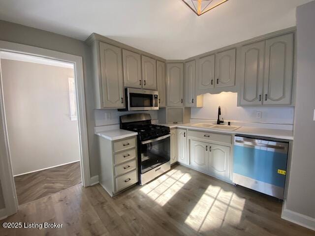 820 Johnson St, Bardstown, KY 40004 - kitchen with appliances with stainless steel finishes, a sink, light countertops, baseboards, and wood finished floors