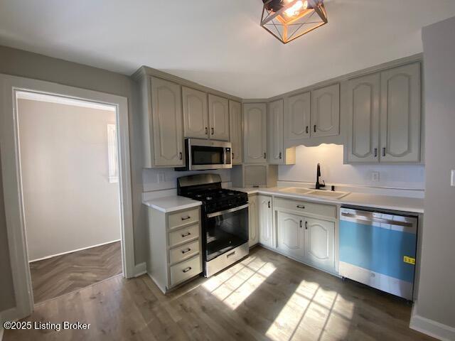 820 Johnson St, Bardstown, KY 40004 - kitchen featuring appliances with stainless steel finishes, a sink, light countertops, baseboards, and parquet flooring