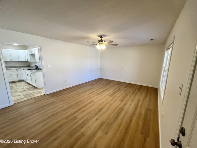171 Old Kentucky 49, Loretto, KY 40037 - unfurnished living room featuring a sink, ceiling fan, light wood-style flooring, and baseboards