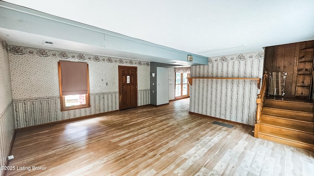 1250 Arnold School Rd, Webster, KY 40176 - unfurnished living room with wallpapered walls, wood finished floors, stairs, baseboards, and wainscoting