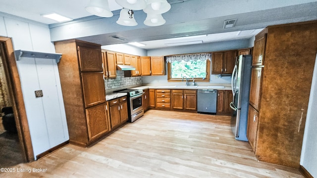 1250 Arnold School Rd, Webster, KY 40176 - kitchen featuring appliances with stainless steel finishes, a sink, under cabinet range hood, light wood-style flooring, and backsplash