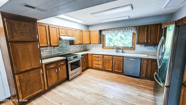 1250 Arnold School Rd, Webster, KY 40176 - kitchen featuring appliances with stainless steel finishes, a sink, light wood-style flooring, under cabinet range hood, and light countertops