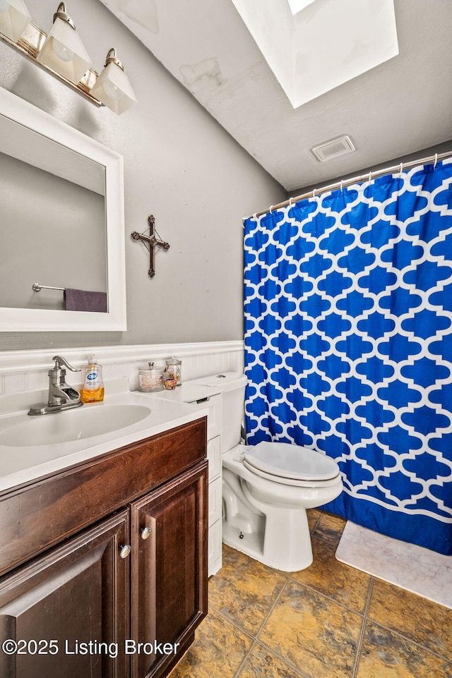 5202 Baywood Dr, Louisville, KY 40241 - bathroom featuring toilet, a skylight, vanity, a wainscoted wall, and a shower with shower curtain