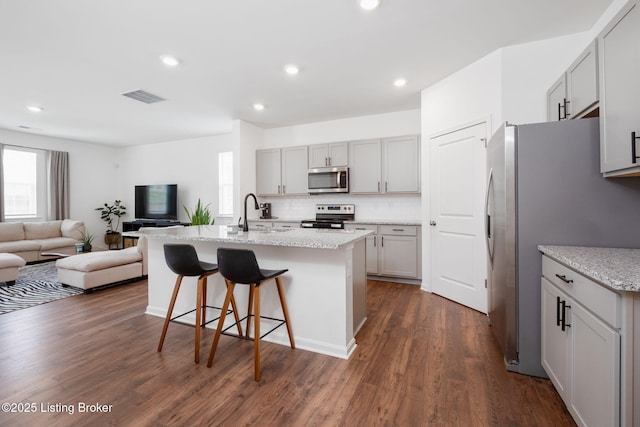 5806 Kellie Woods Dr, Louisville, KY 40258 - kitchen featuring appliances with stainless steel finishes, open floor plan, gray cabinetry, a breakfast bar area, and dark wood-type flooring