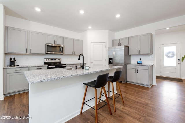 5806 Kellie Woods Dr, Louisville, KY 40258 - kitchen with gray cabinetry, appliances with stainless steel finishes, decorative backsplash, dark wood finished floors, and recessed lighting