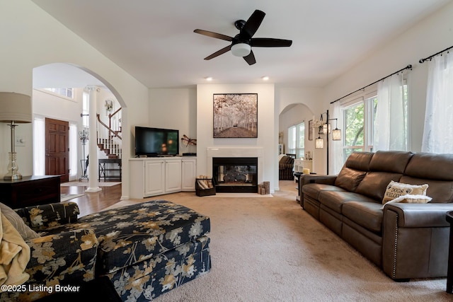 13512 Springs Station Rd, Louisville, KY 40245 - living room with arched walkways, a fireplace with flush hearth, ceiling fan, light carpet, and stairs