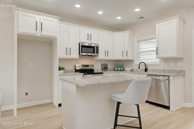 LOT27 Brookley Dr, Louisville, KY 40229 - kitchen with stainless steel appliances, light wood-style floors, white cabinetry, a center island, and a sink