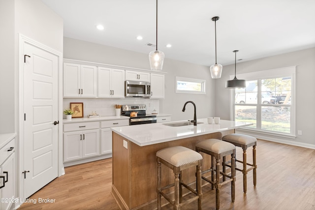 801 Artisan Pkwy, La Grange, KY 40031 - kitchen with appliances with stainless steel finishes, a sink, light wood finished floors, decorative backsplash, and a breakfast bar