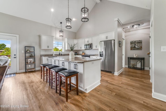458 Christman Ln, Shepherdsville, KY 40165 - kitchen with stainless steel appliances, a kitchen island, high vaulted ceiling, white cabinetry, and light wood-style floors