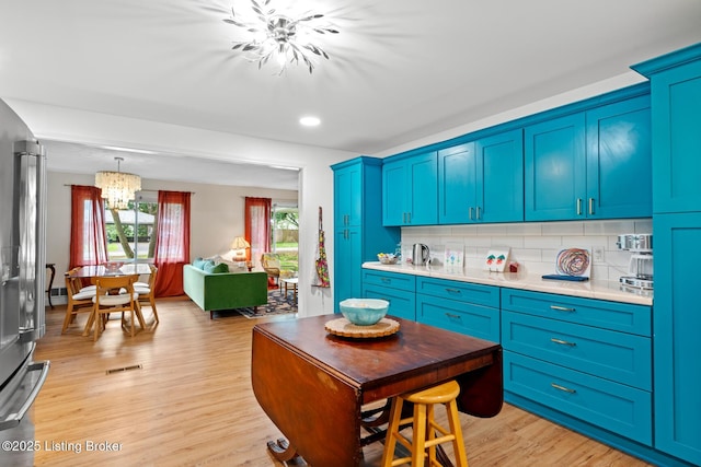 607 Edgemont Rd, Irvington, KY 40146 - kitchen with a chandelier, light countertops, tasteful backsplash, light wood finished floors, and blue cabinetry
