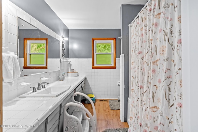 607 Edgemont Rd, Irvington, KY 40146 - bathroom featuring vanity, wood finished floors, plenty of natural light, tile walls, and wainscoting