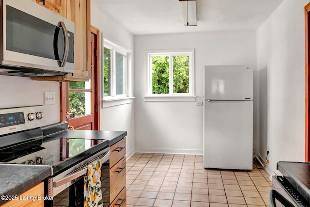 4309 Cavelle Ave, Louisville, KY 40213 - kitchen featuring appliances with stainless steel finishes, dark countertops, light tile patterned floors, and baseboards