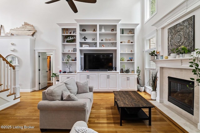 13318 Stepping Stone Way, Louisville, KY 40299 - living room featuring a ceiling fan, a fireplace, stairs, a towering ceiling, and light wood-style flooring