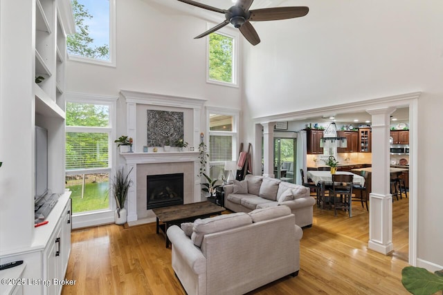 13318 Stepping Stone Way, Louisville, KY 40299 - living room with a towering ceiling, a ceiling fan, a fireplace, decorative columns, and light wood-type flooring