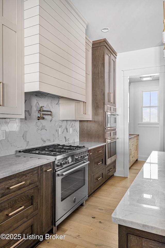 4907 Sycamore Ridge Ln, La Grange, KY 40031 - kitchen with stainless steel appliances, light wood-style flooring, light stone counters, backsplash, and dark brown cabinetry
