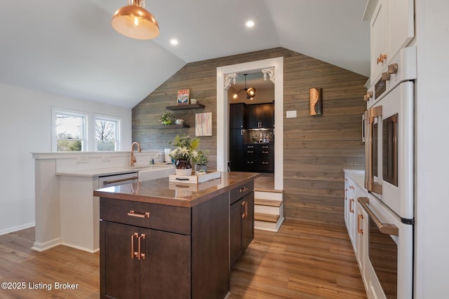 5971 State Road 62, Georgetown, IN 47122 - kitchen with wood walls, vaulted ceiling, dark brown cabinetry, a kitchen island, and light wood-style floors