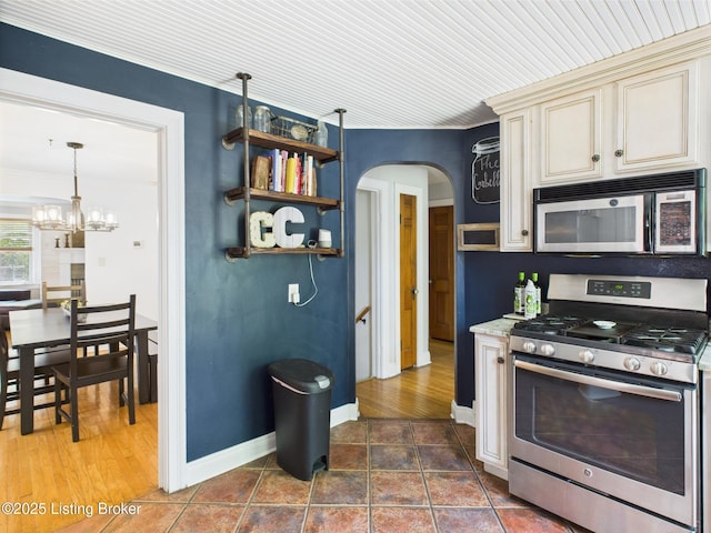 4932 Southern Pkwy, Louisville, KY 40214 - kitchen with stainless steel appliances, cream cabinets, arched walkways, a chandelier, and ornamental molding