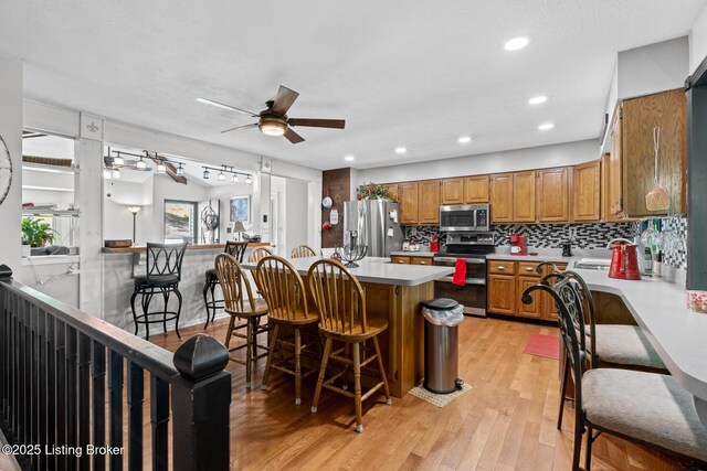 94 Tarnwood Dr, Brandenburg, KY 40108 - kitchen featuring appliances with stainless steel finishes, brown cabinets, light countertops, a breakfast bar, and light wood-type flooring
