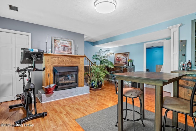 94 Tarnwood Dr, Brandenburg, KY 40108 - dining area featuring a fireplace with raised hearth, wood finished floors, and a textured ceiling