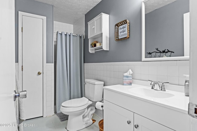 94 Tarnwood Dr, Brandenburg, KY 40108 - bathroom featuring a textured ceiling, tile walls, toilet, vanity, and wainscoting