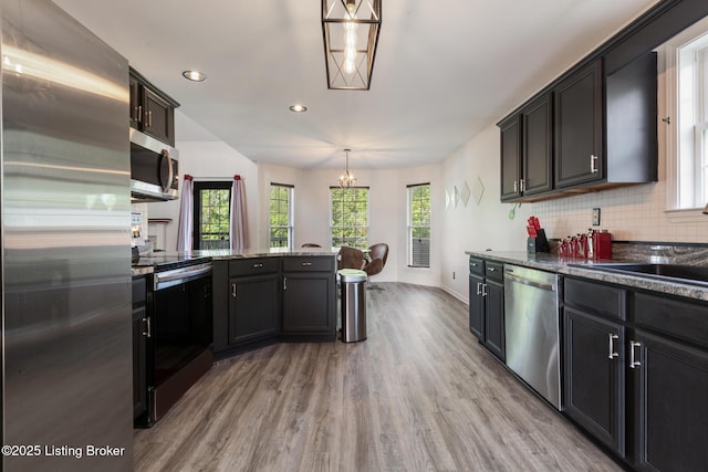 6820 Grandfield Rd, Louisville, KY 40258 - kitchen with appliances with stainless steel finishes, light wood-type flooring, a chandelier, tasteful backsplash, and a peninsula