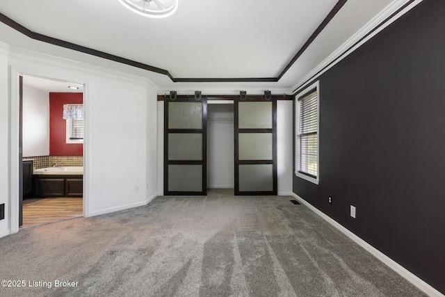 6820 Grandfield Rd, Louisville, KY 40258 - unfurnished bedroom featuring a barn door, carpet floors, crown molding, baseboards, and connected bathroom
