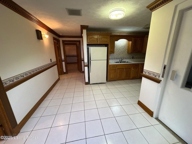 5309 Bardstown Rd, Springfield, KY 40069 - kitchen with freestanding refrigerator, brown cabinetry, crown molding, light tile patterned flooring, and light countertops