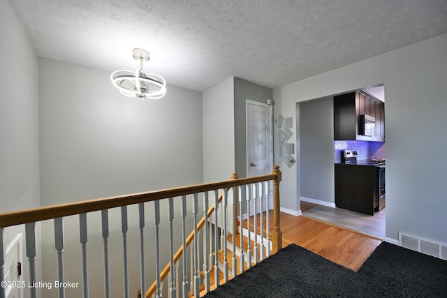 7514 Pimlico Dr, Louisville, KY 40214 - corridor featuring an upstairs landing, a chandelier, light wood-type flooring, baseboards, and a textured ceiling