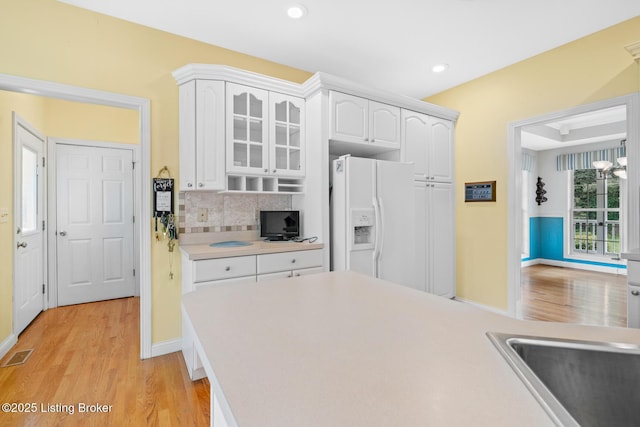 966 Lawrence St, Brandenburg, KY 40108 - kitchen featuring white refrigerator with ice dispenser, light wood-style floors, light countertops, white cabinets, and backsplash