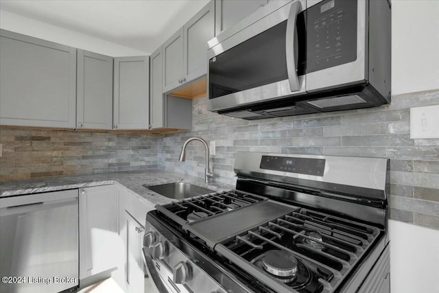 4104 Hispanyola Ct, Louisville, KY 40229 - kitchen with stainless steel appliances, a sink, gray cabinets, light stone countertops, and backsplash