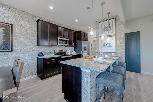 101 Exploration Unit 61A, Shelbyville, KY 40065 - kitchen featuring stainless steel appliances, light wood-style floors, light stone countertops, a kitchen breakfast bar, and dark brown cabinetry