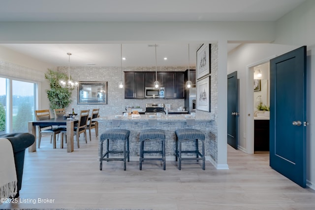 101 Exploration Unit 61A, Shelbyville, KY 40065 - kitchen featuring stainless steel appliances, a breakfast bar area, a chandelier, light wood finished floors, and pendant lighting