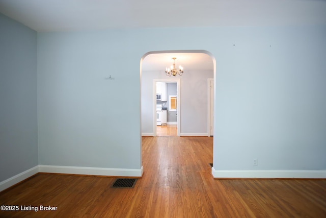 3521 Warner Ave, Louisville, KY 40207 - empty room with arched walkways, wood finished floors, a chandelier, and baseboards