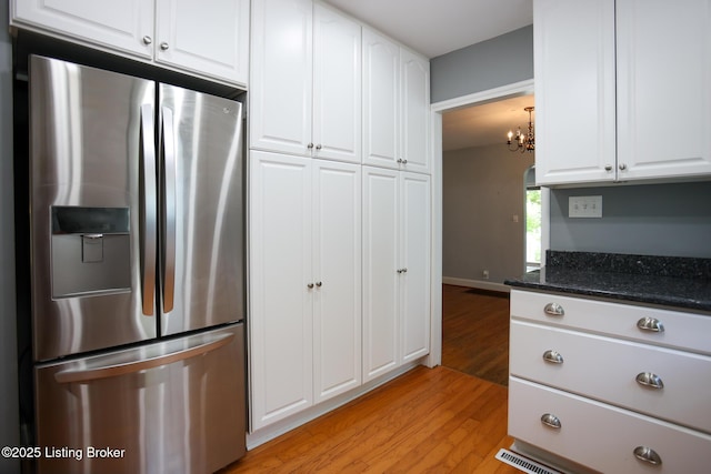 3521 Warner Ave, Louisville, KY 40207 - kitchen featuring stainless steel fridge with ice dispenser, light wood finished floors, white cabinetry, a chandelier, and dark stone counters