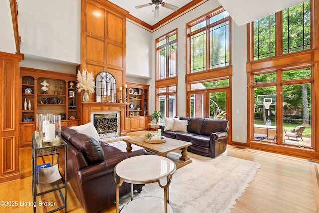 1014 Anchorage Woods Cir, Anchorage, KY 40223 - living area with a high ceiling, light wood-style flooring, a premium fireplace, ceiling fan, and ornamental molding