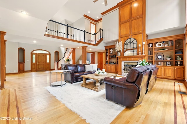 1014 Anchorage Woods Cir, Anchorage, KY 40223 - living room with a towering ceiling, stairway, light wood-type flooring, a fireplace, and arched walkways