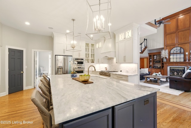 1014 Anchorage Woods Cir, Anchorage, KY 40223 - kitchen with appliances with stainless steel finishes, a sink, white cabinets, premium range hood, and light stone countertops