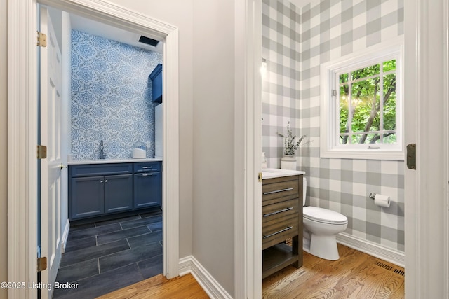1014 Anchorage Woods Cir, Anchorage, KY 40223 - half bath with vanity, toilet, wallpapered walls, wood finished floors, and baseboards