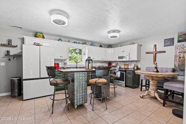 2327 Highgrove Rd, Coxs Creek, KY 40013 - kitchen with white appliances, white cabinetry, light tile patterned flooring, decorative backsplash, and a kitchen bar