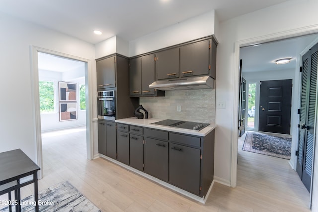 508 Wilderness Rd, Louisville, KY 40214 - kitchen featuring under cabinet range hood, black electric cooktop, oven, light wood finished floors, and backsplash
