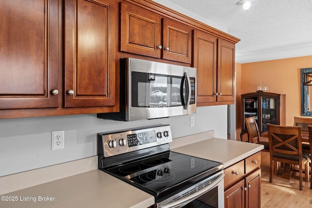 126 Deep Springs Dr, Bardstown, KY 40004 - kitchen featuring stainless steel appliances, light countertops, a textured ceiling, brown cabinetry, and light wood finished floors