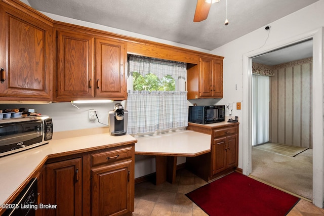 kitchen with black microwave, light countertops, a ceiling fan, brown cabinets, and dishwashing machine