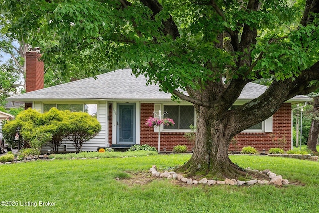 view of front of house featuring a chimney, a front yard, and brick siding