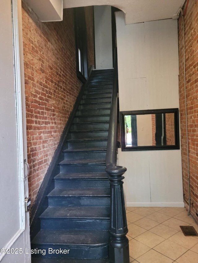224 E Oak St, Louisville, KY 40203 - staircase with brick wall, tile patterned floors, and baseboards