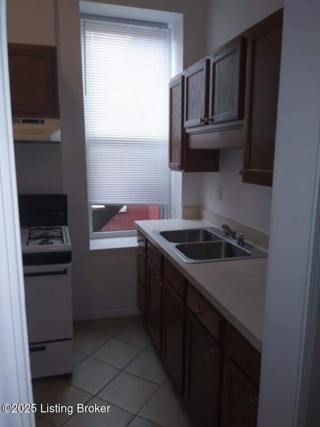 224 E Oak St, Louisville, KY 40203 - kitchen with electric range oven, under cabinet range hood, a sink, light tile patterned floors, and light countertops