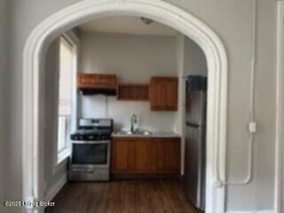 224 E Oak St, Louisville, KY 40203 - kitchen with gas range, arched walkways, brown cabinets, dark wood-style flooring, and a sink