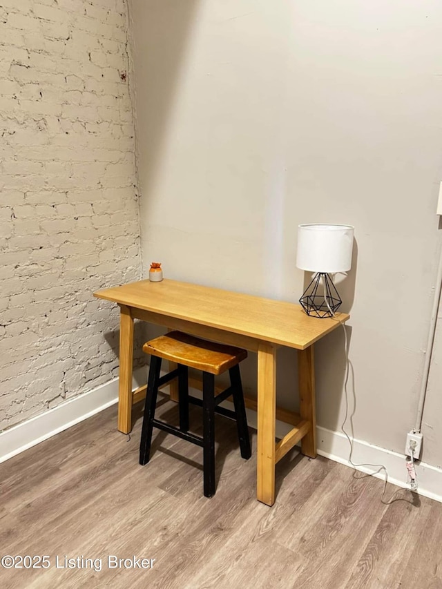 224 E Oak St, Louisville, KY 40203 - dining area with baseboards, wood finished floors, and brick wall